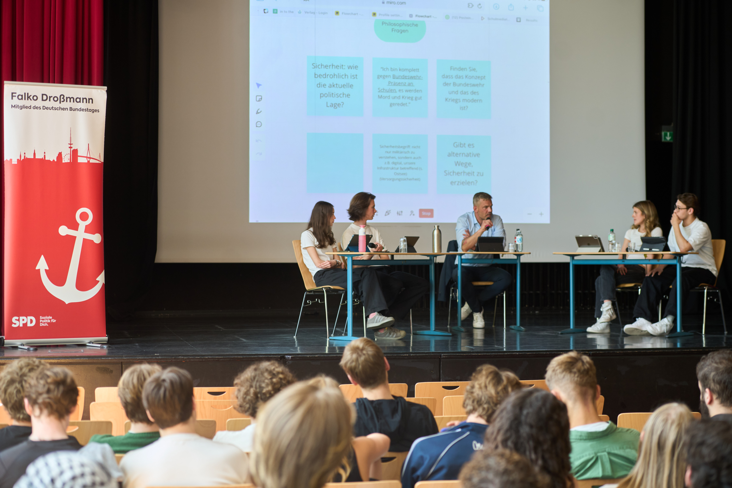 Der Politiker Heiko Droßmann diskutiert mit Schülern der Klosterschule auf der Bühne der Aula der Klosterschule
