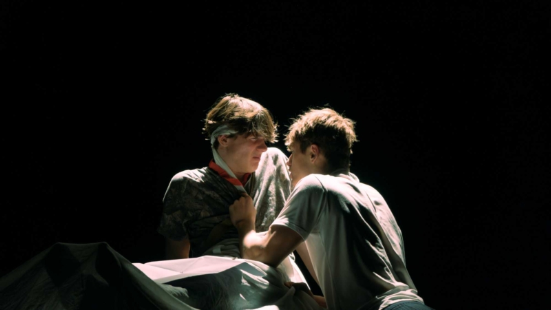 zwei Schauspieler stehen sich vor dunklem Hintergrund gegenüber