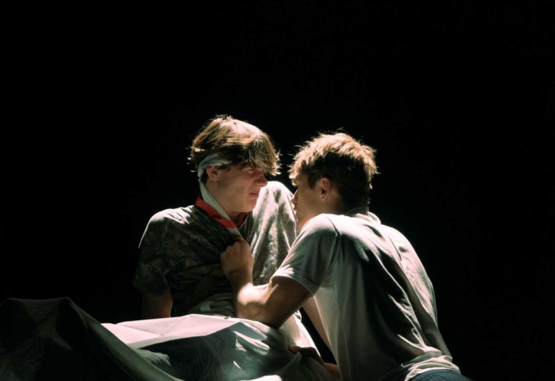 zwei Schauspieler stehen sich vor dunklem Hintergrund gegenüber