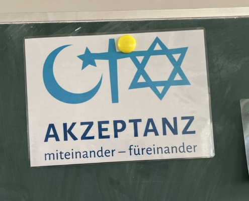 Schild mit Mondsichel, Kreuz und Davidstern und der Beschriftung "miteinander - füreinander"