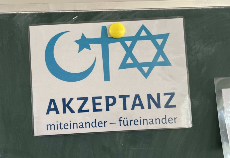 Schild mit Mondsichel, Kreuz und Davidstern und der Beschriftung "miteinander - füreinander"