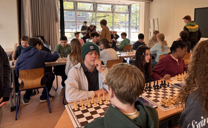 Schüler sitzen in einem Raum an Tischen und spielen Schach