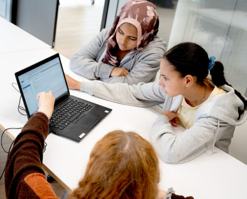 Schülerinnen sitzen vor einem Laptop