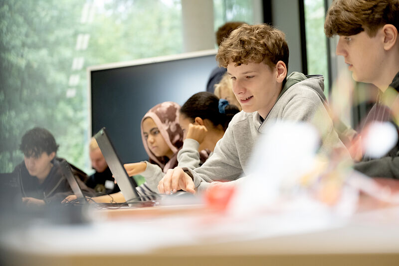 Schüler sitzen vor einem Laptop